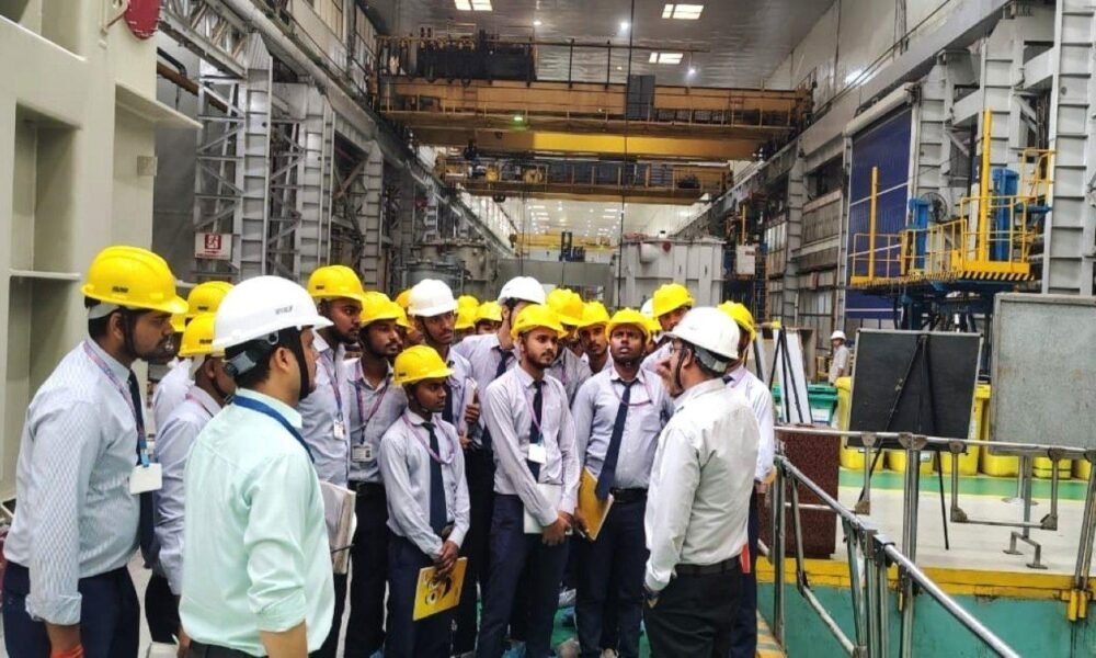 Technical education faculty interacting with industry professionals in a manufacturing facility.