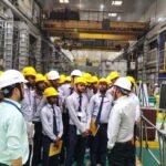 Technical education faculty interacting with industry professionals in a manufacturing facility.