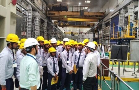 Technical education faculty interacting with industry professionals in a manufacturing facility.