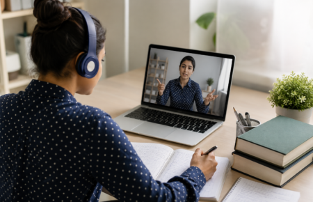 University student attending an online postgraduate lecture on a laptop while studying from home.